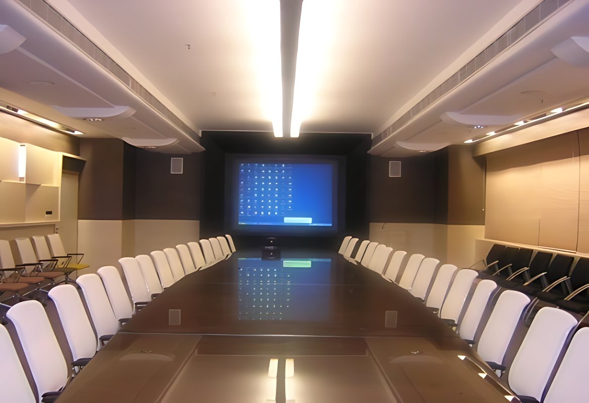 ONGC board room: a long table lined with white chairs facing a large screen